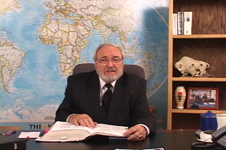 A man sitting center with an open book and a map behind him 