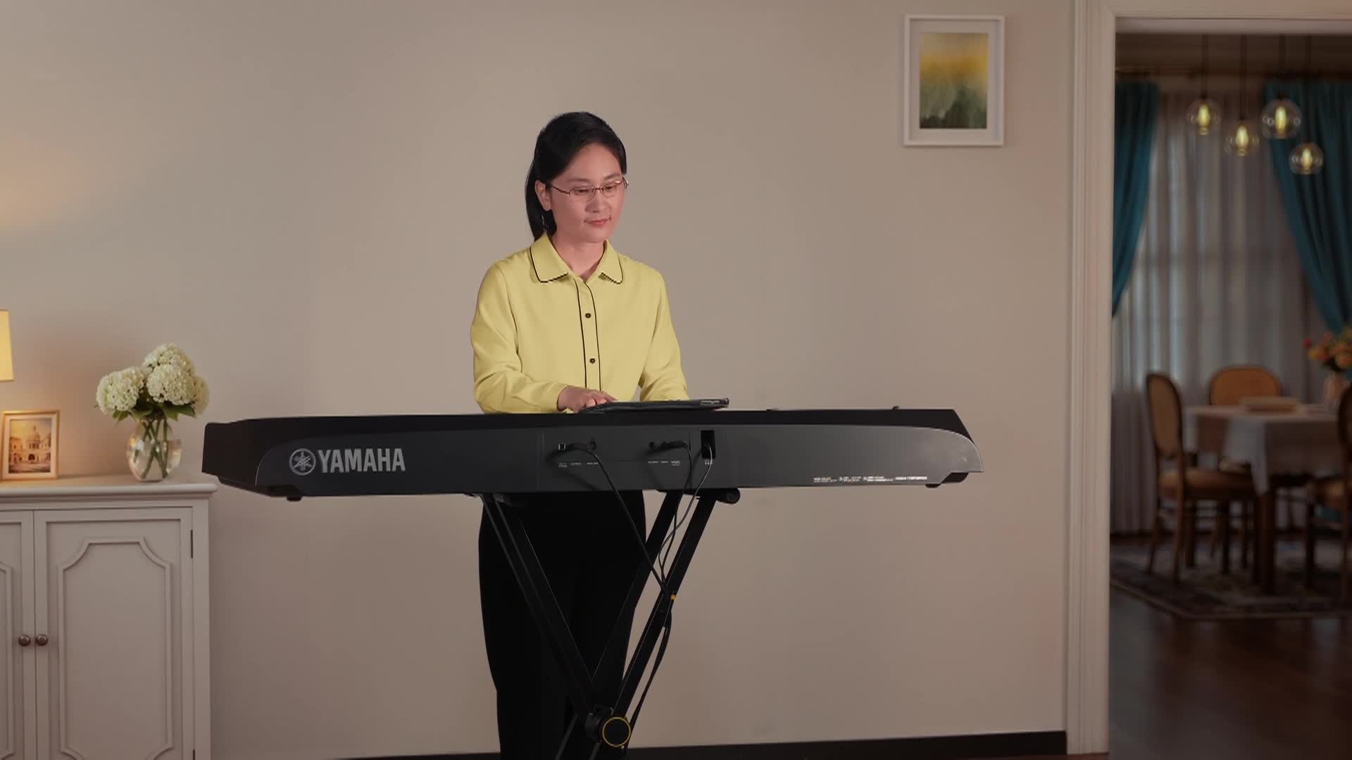 A woman standing at an electric keyboard inside. 